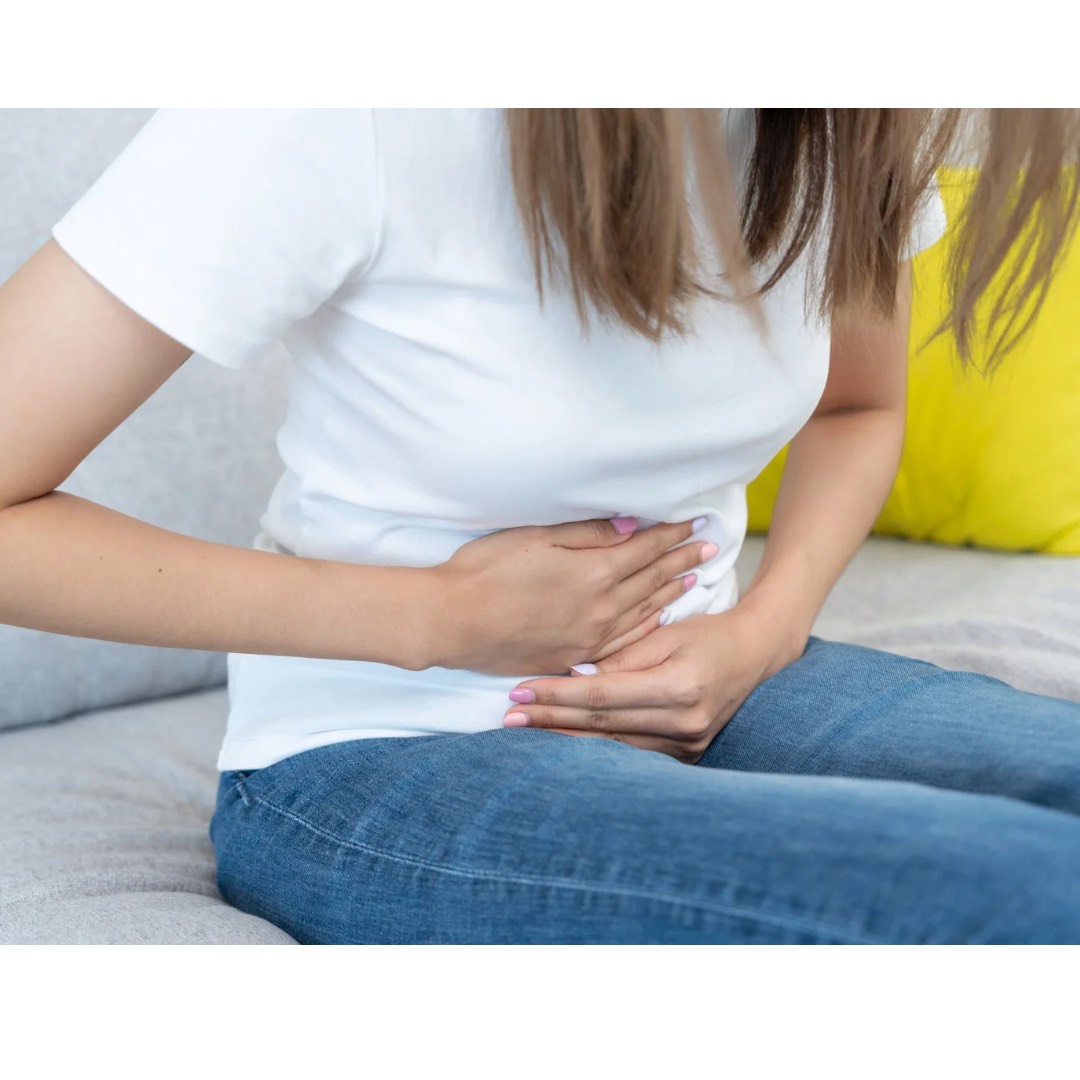 便秘に悩む女性がお腹を押さえて苦しそうにしています
